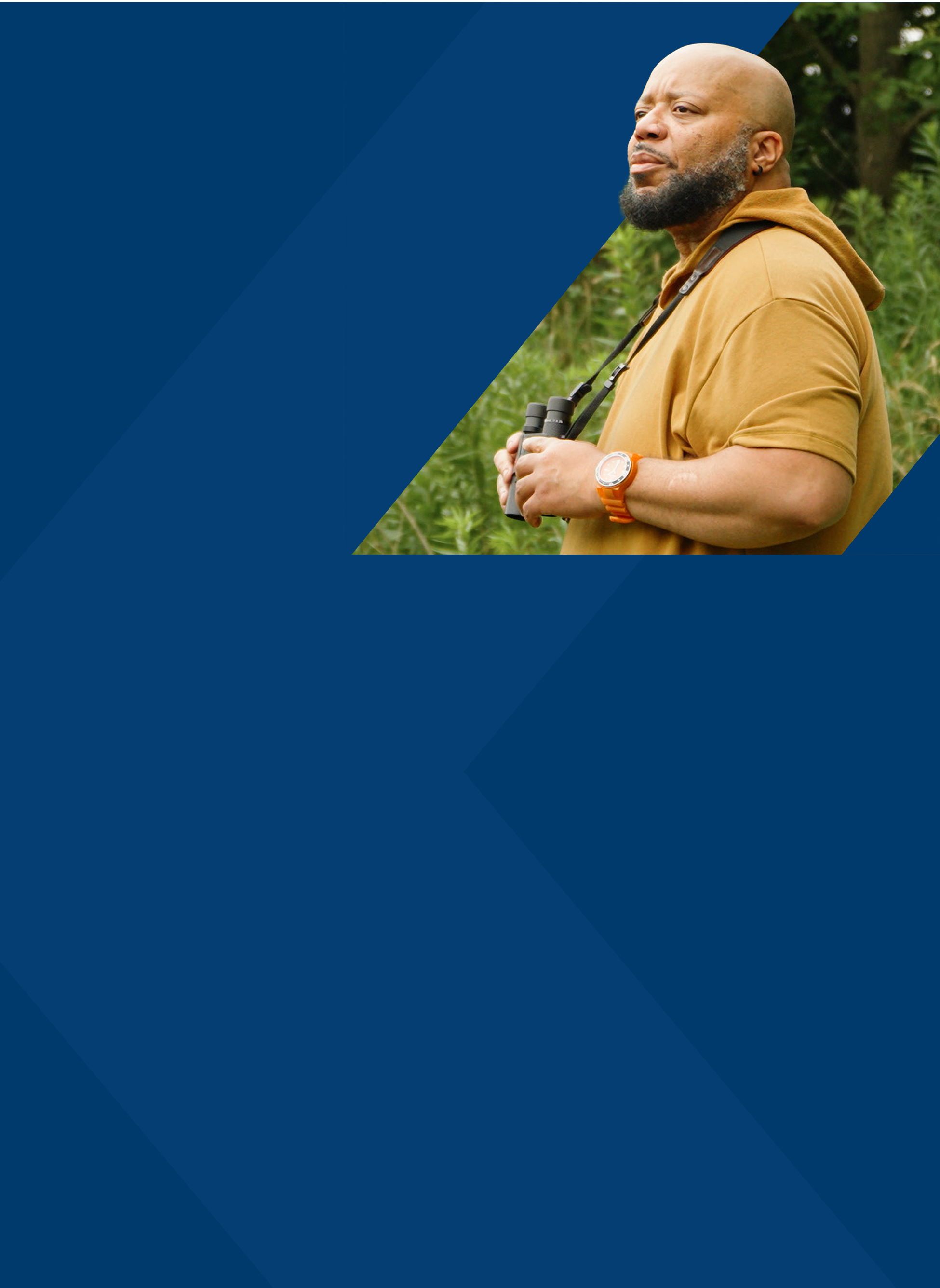 Al, a PYLARIFY patient, standing outside in nature, holding binoculars