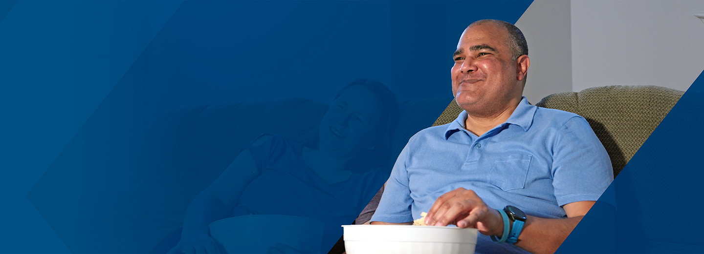 Eric, a PYLARIFY patient, sitting on the couch and eating popcorn