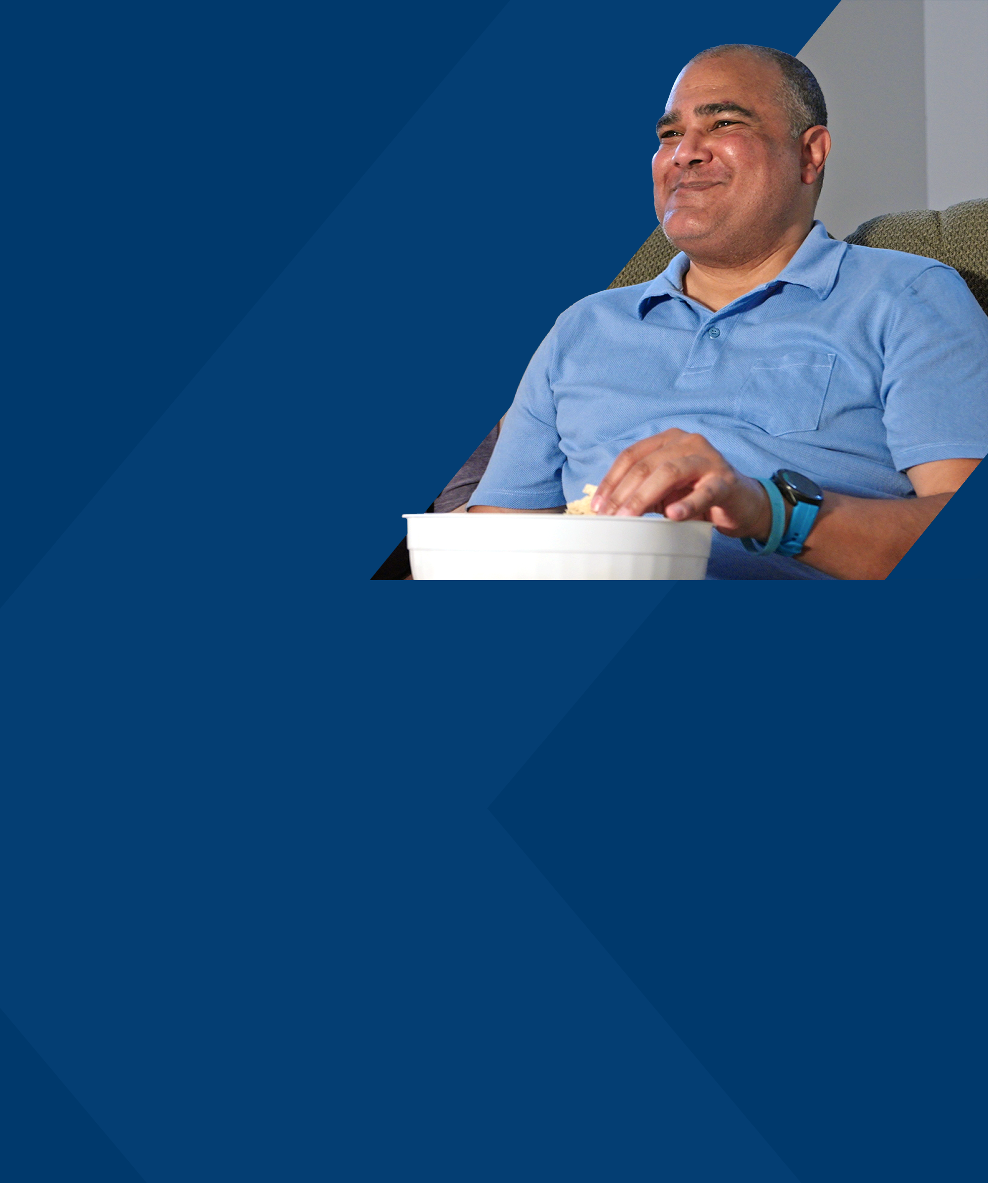 Eric, a PYLARIFY patient, sitting on the couch and eating popcorn